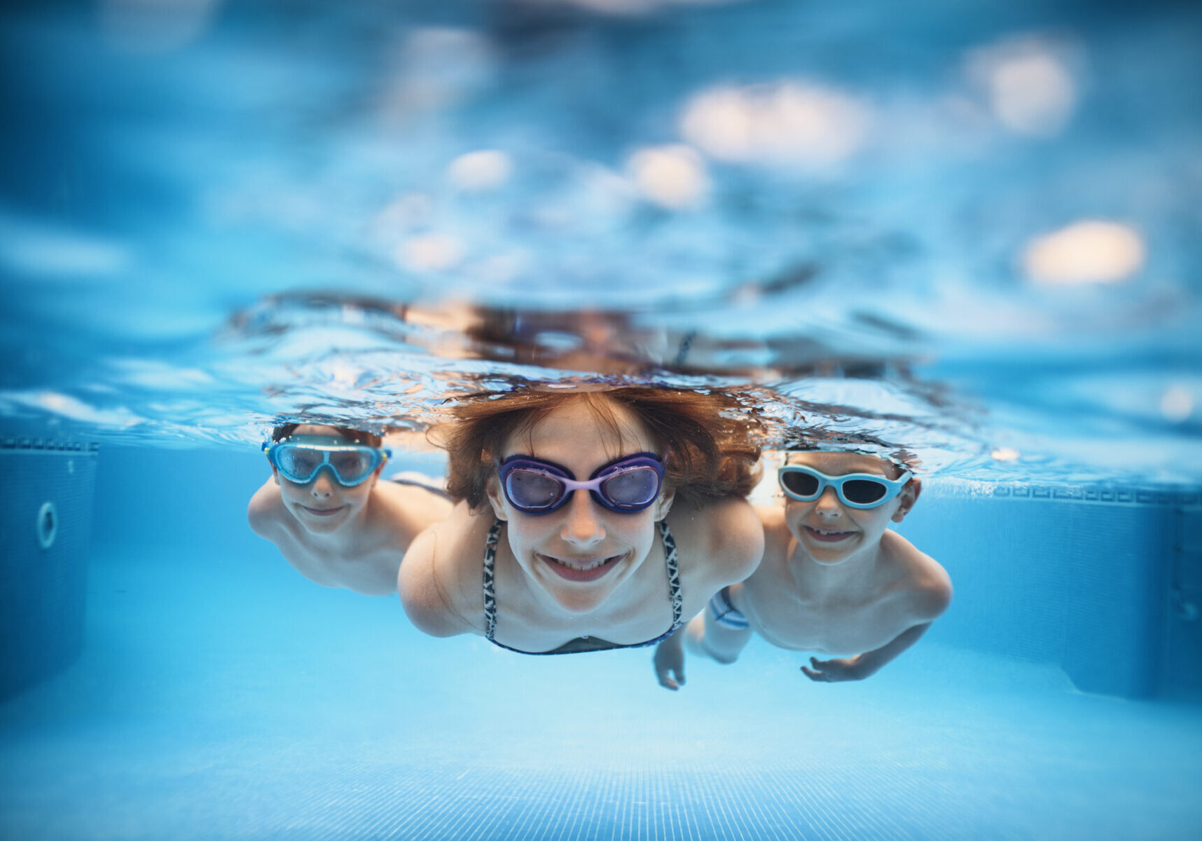 Three smiling kids enjoying underwater swim in the pool.
Nikon D810